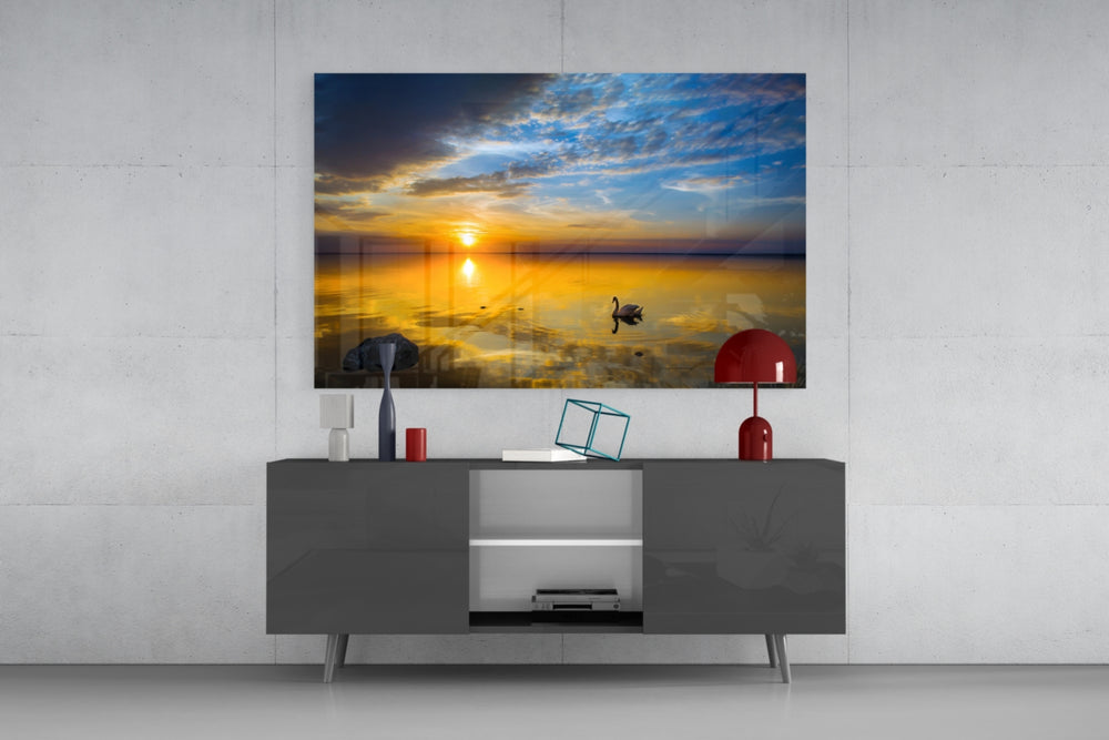 Fine art nature photography – solitary swan on glassy golden lake at sunset, dramatic layered sky with orange glow and blue clouds
