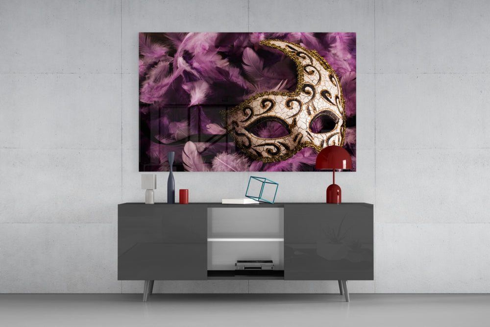 Fine art still life – elegant white Venetian mask with ornate gold patterns lying on scattered purple and pink feathers