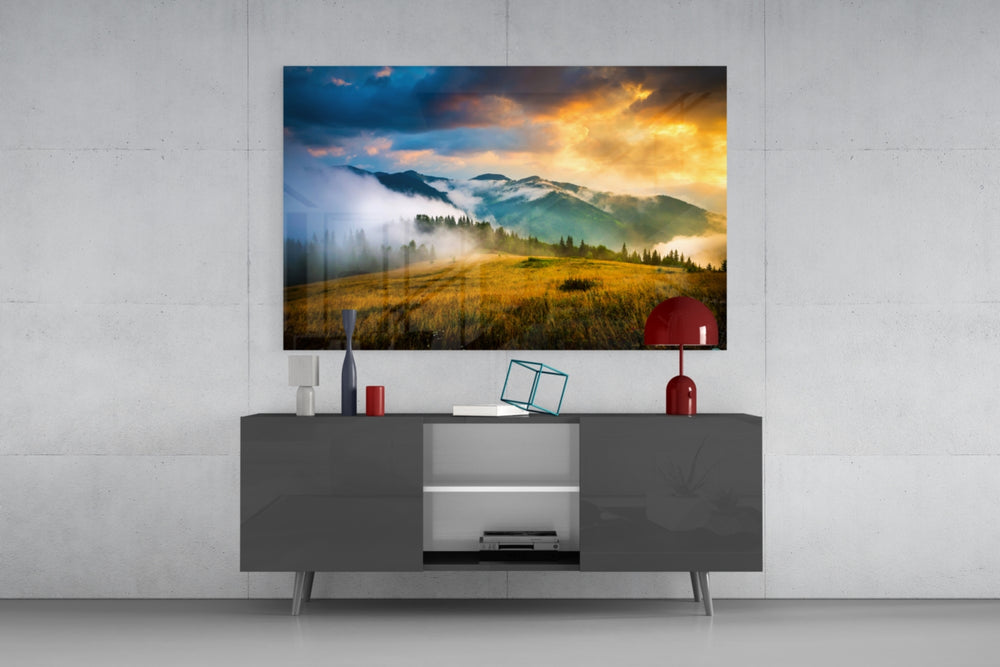 Fine art nature photography – misty mountain peaks rising above golden meadow under dramatic multicolor sky with storm clouds and golden light