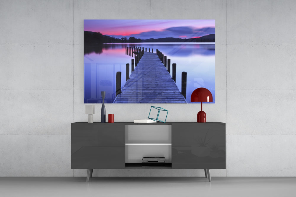 Fine art photography – wooden dock with mooring posts extending into mirror-still lake at dusk, sky transitioning from pink to deep violet and blue