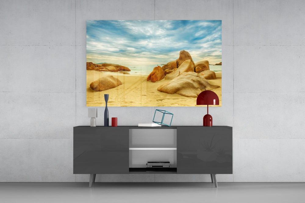 Fine art photography – weathered golden granite boulders on pristine tropical beach, warm afternoon light with turquoise sea and dramatic clouds