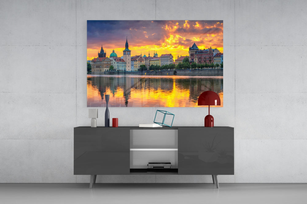 Fine art photography – Prague historic waterfront at dramatic golden sunset, colorful spired buildings reflected in mirror-calm Vltava River