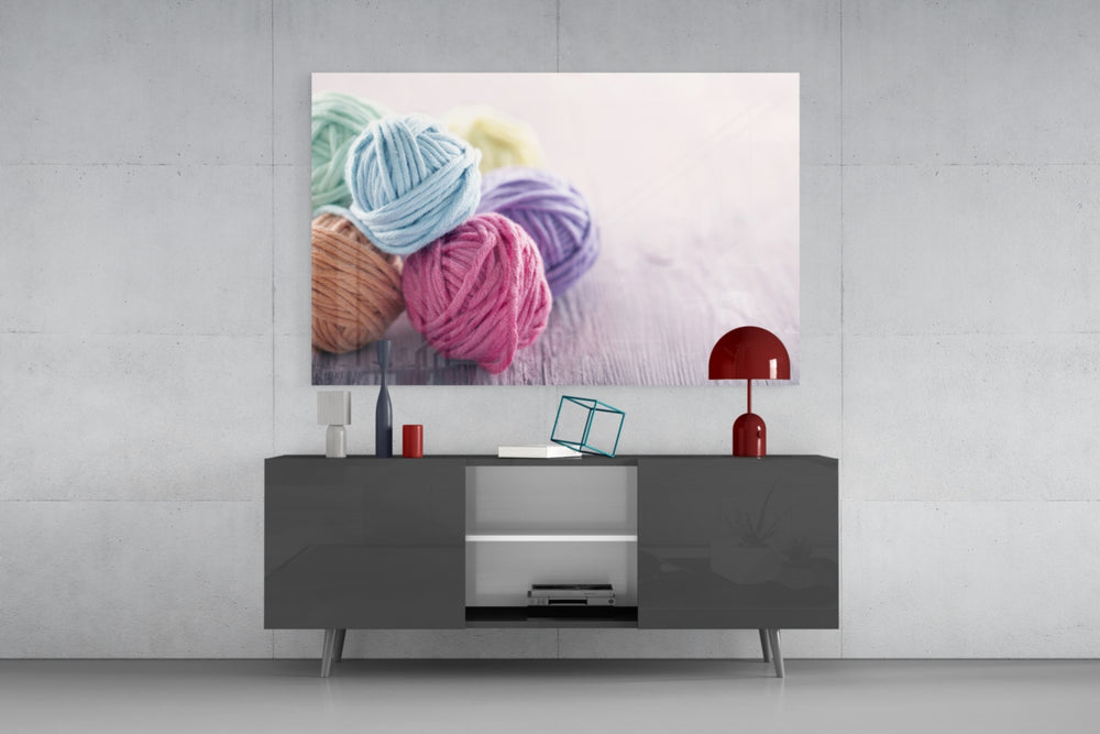 Fine art still life – arrangement of pastel-coloured yarn balls in mint, sky blue, rose pink and lavender on light grey wooden surface