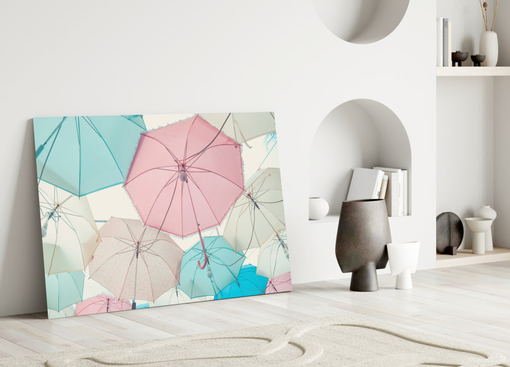 Umbrellas glass wall art styled above a bed in a soft pastel bedroom