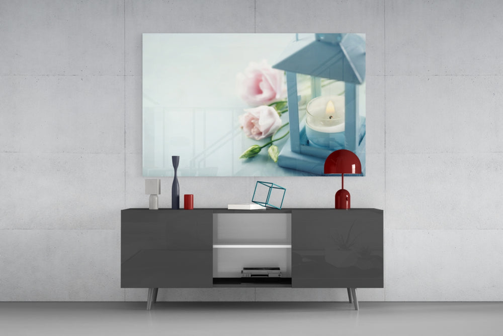 Fine art still life – blue lantern with glowing candle beside soft pink roses and buds on pale aqua blue background
