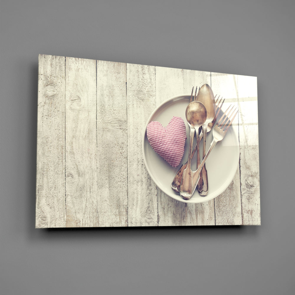 Close-up detail of silver cutlery and pink fabric heart on wood