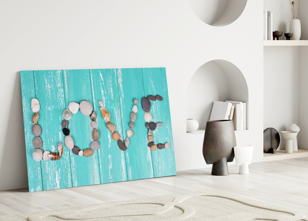 Close-up detail of LOVE spelled in stones and shells on turquoise wood