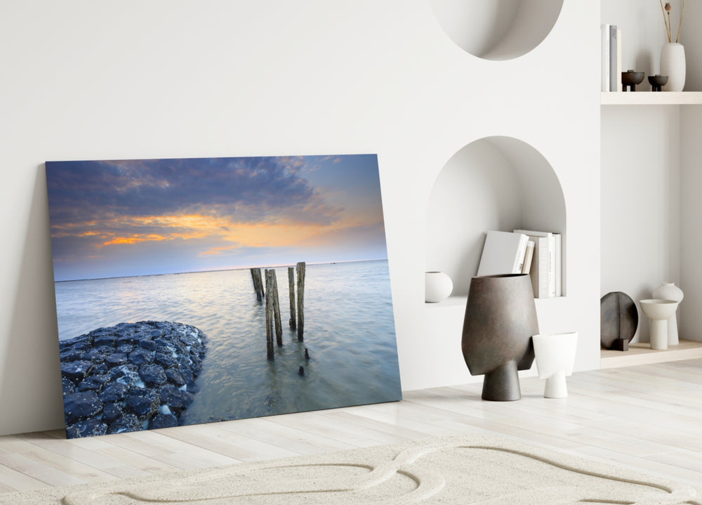 Close-up detail of the wooden pilings and basalt rocks at sunset