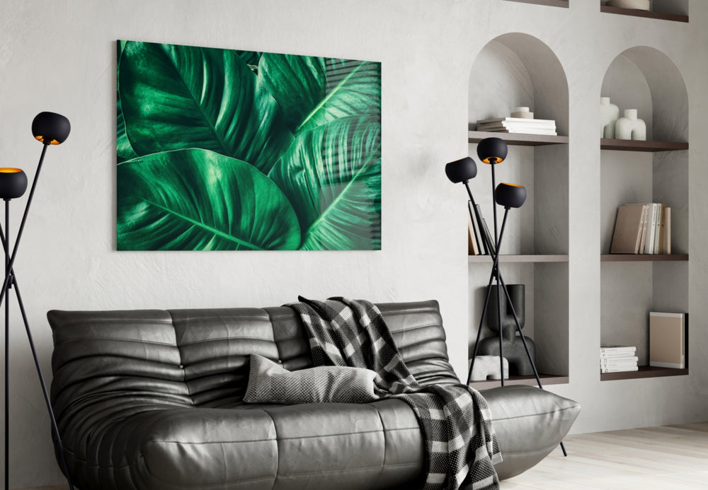 Green Tropical Leaf glass wall art styled above a sofa in a plant-filled living room