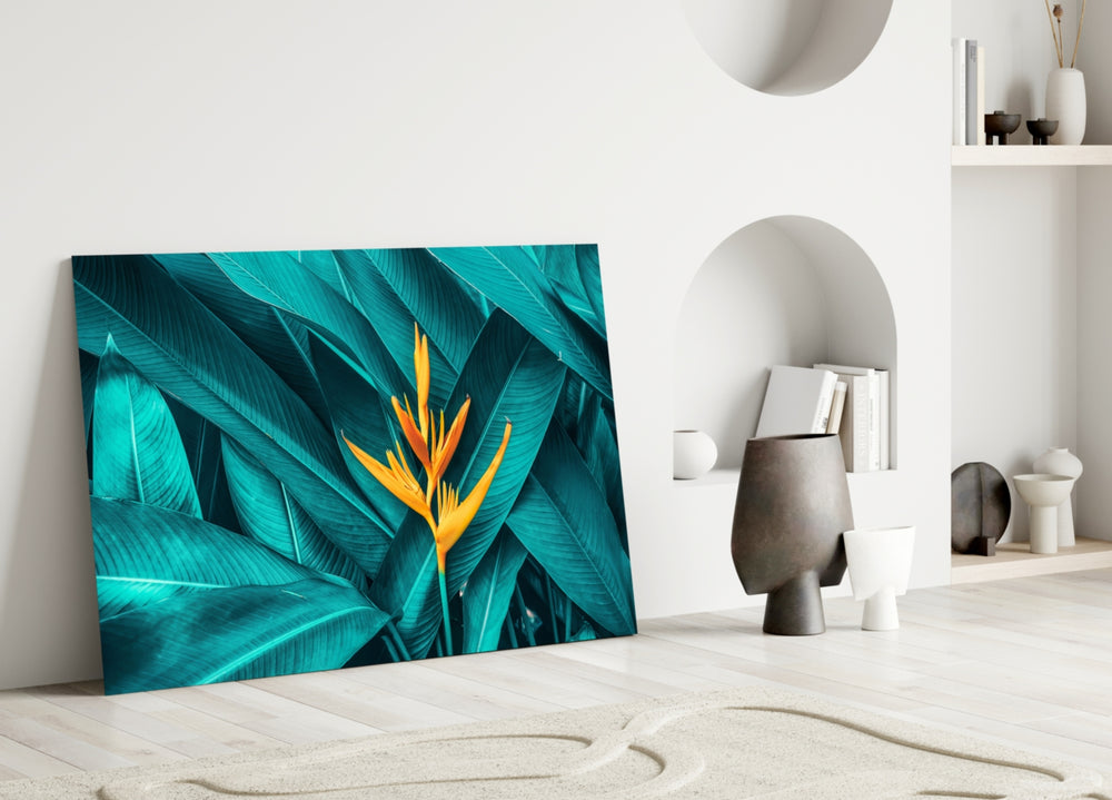 Close-up detail of the orange heliconia rising through teal leaves