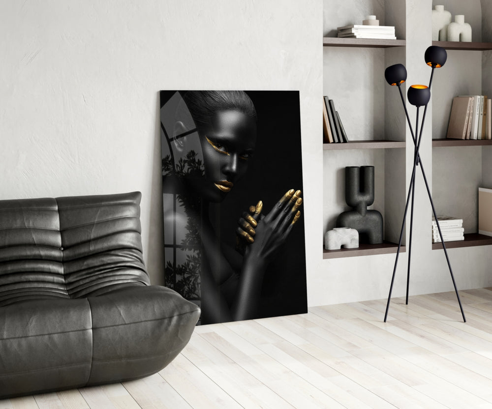 Woman glass wall art styled above a bed in a black-and-gold bedroom
