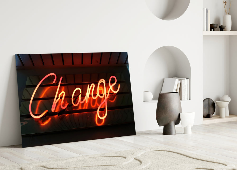 Change Neon glass wall art styled above a side-table in a creative office