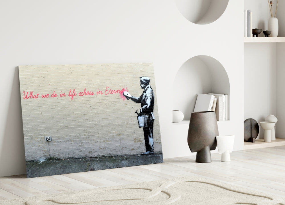 What We Do in Life close-up showing painter spraying pink Eternity quote on cream brick