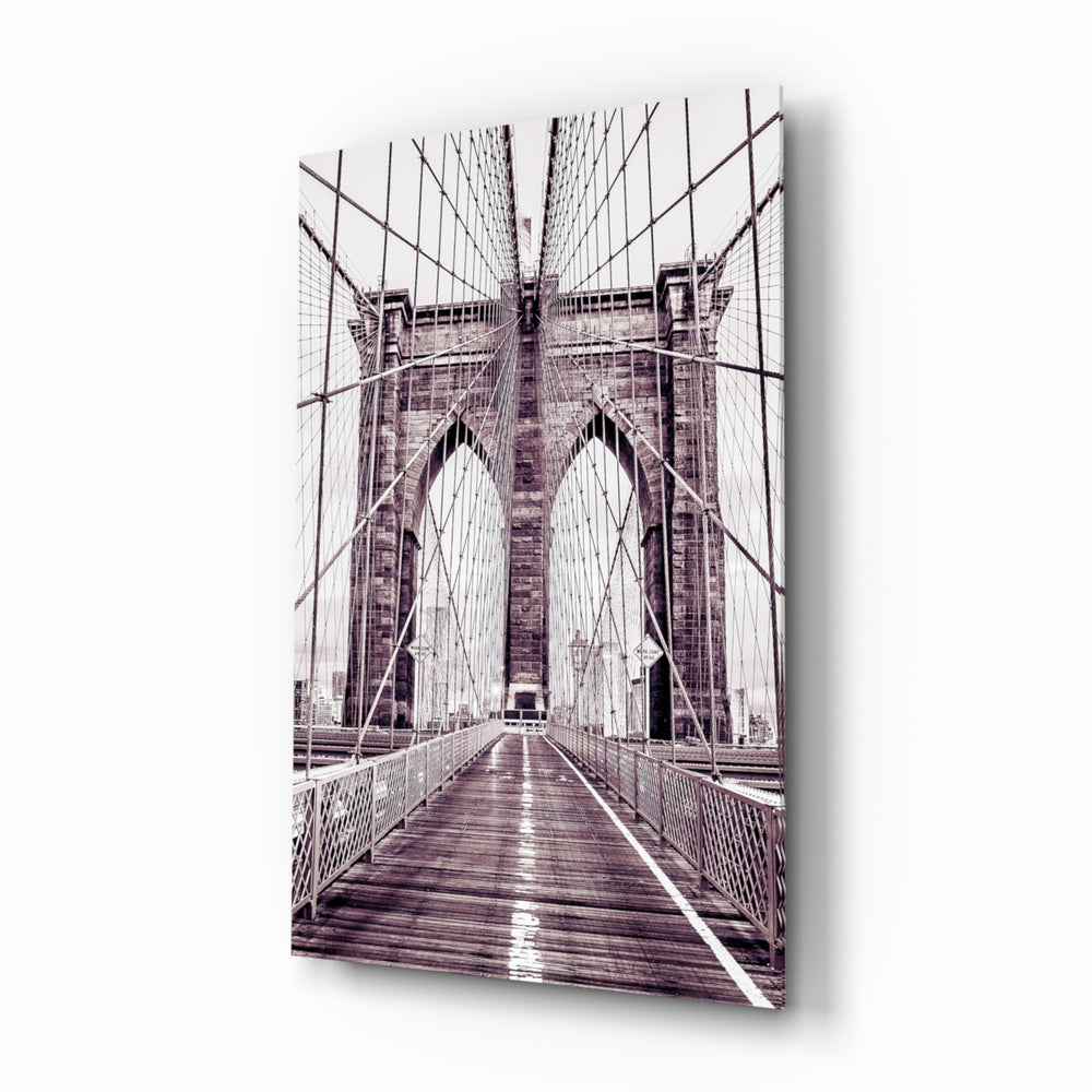 Brooklyn Bridge glass wall art displayed above a linen bed in a dusk-mauve bedroom with rattan nightstands and brushed-brass sconces