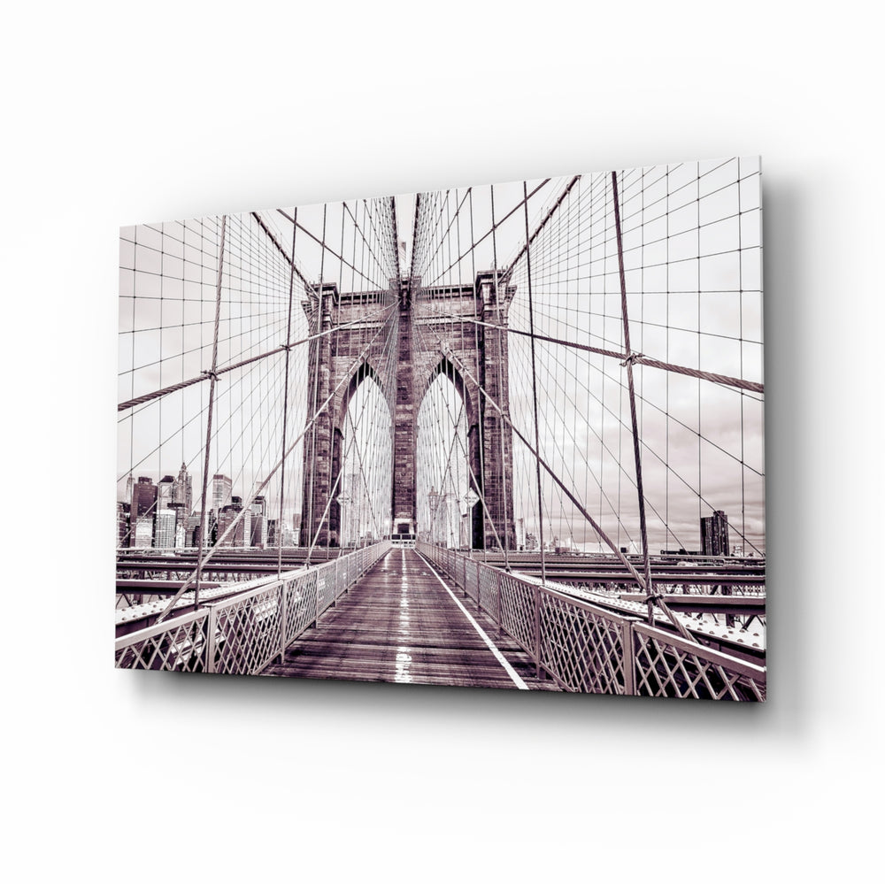 Brooklyn Bridge glass wall art displayed above a linen sofa in a beige living room with rattan armchair and walnut console