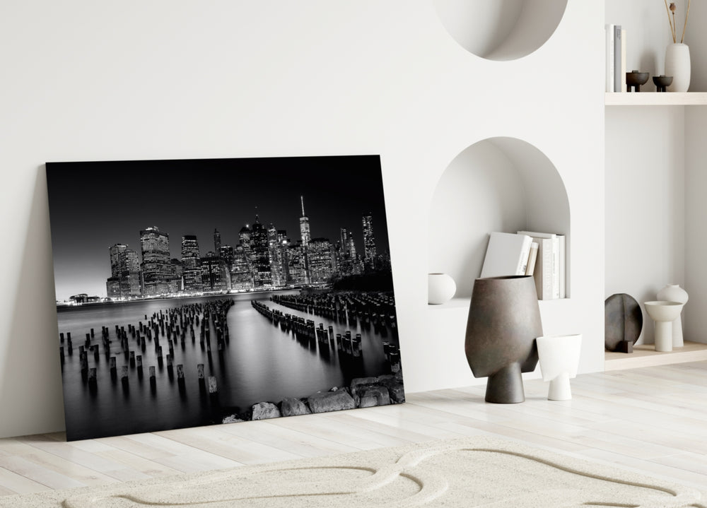 City Night close-up showing Manhattan skyscrapers above mirror water and weathered pilings