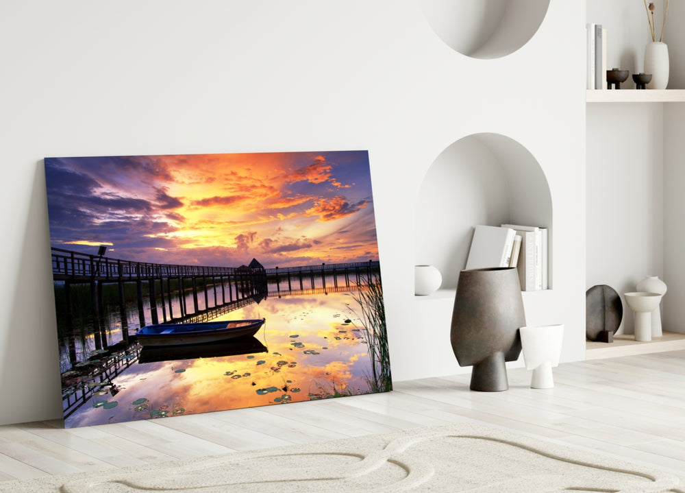 Close-up detail of rowboat and lily pads under a vivid sunset reflection