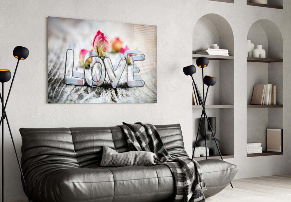 Love glass wall art styled above a bed in a romantic bedroom