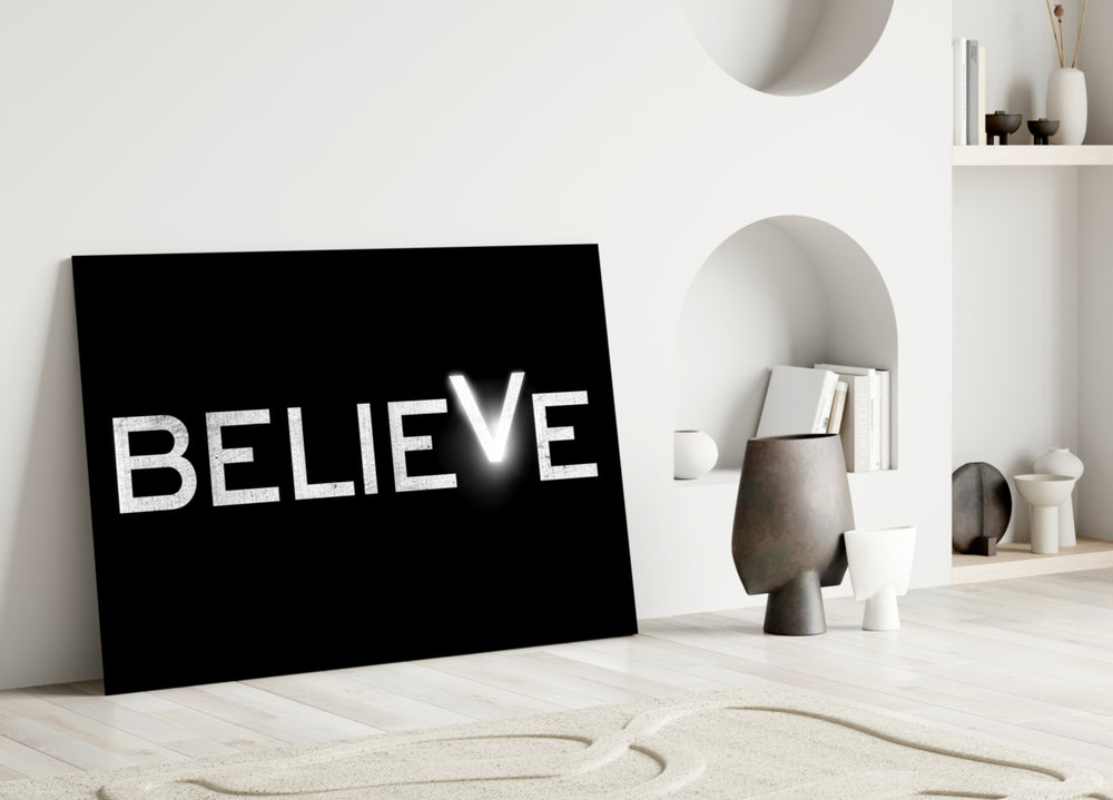 Close-up detail of glowing Believe stencil behind glass