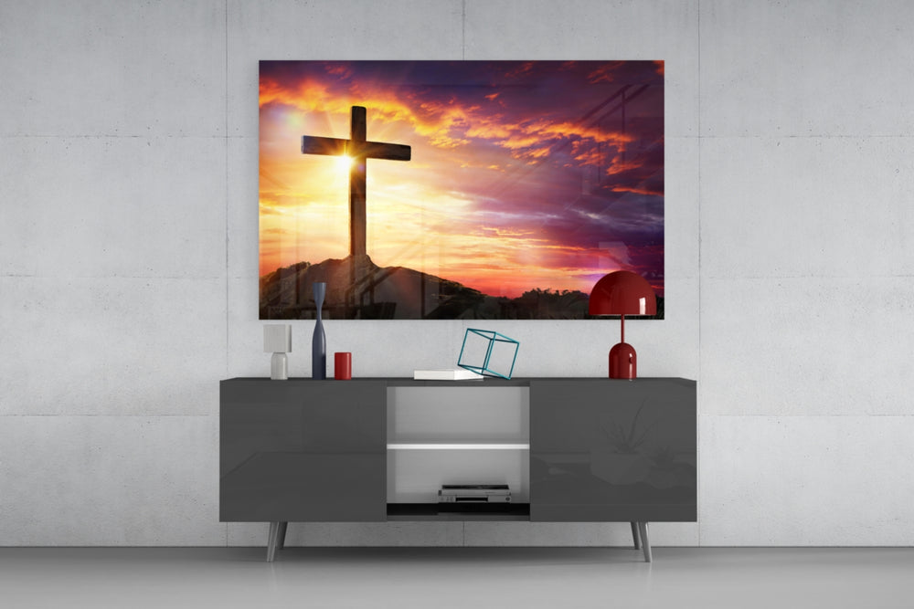 Cross glass wall art catching light to reveal its painted scarlet sunset