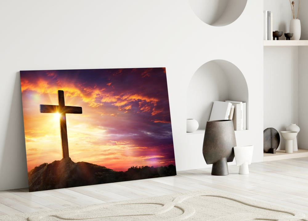 Close-up detail of silhouetted cross and sunburst flare behind glass