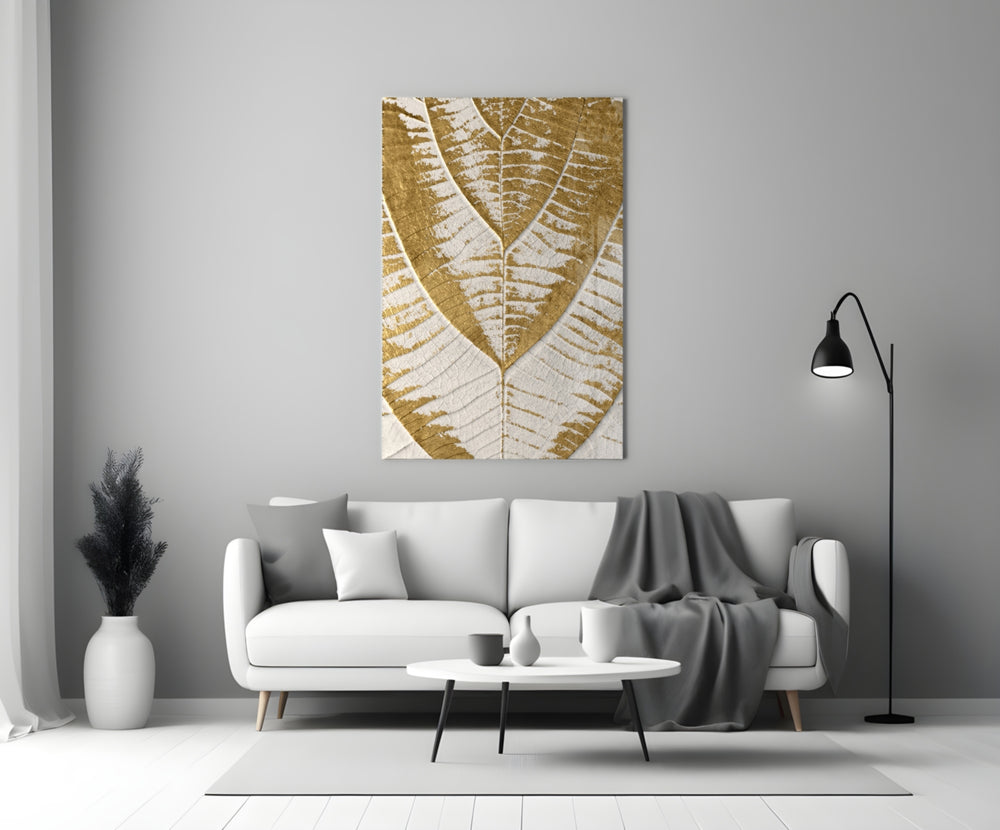 Close-up detail of gilded fern-vein leaf on ivory behind glass
