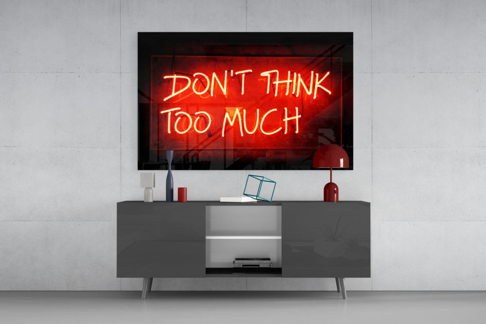 Don't Think Too Much glass wall art catching light to reveal its painted neon glow