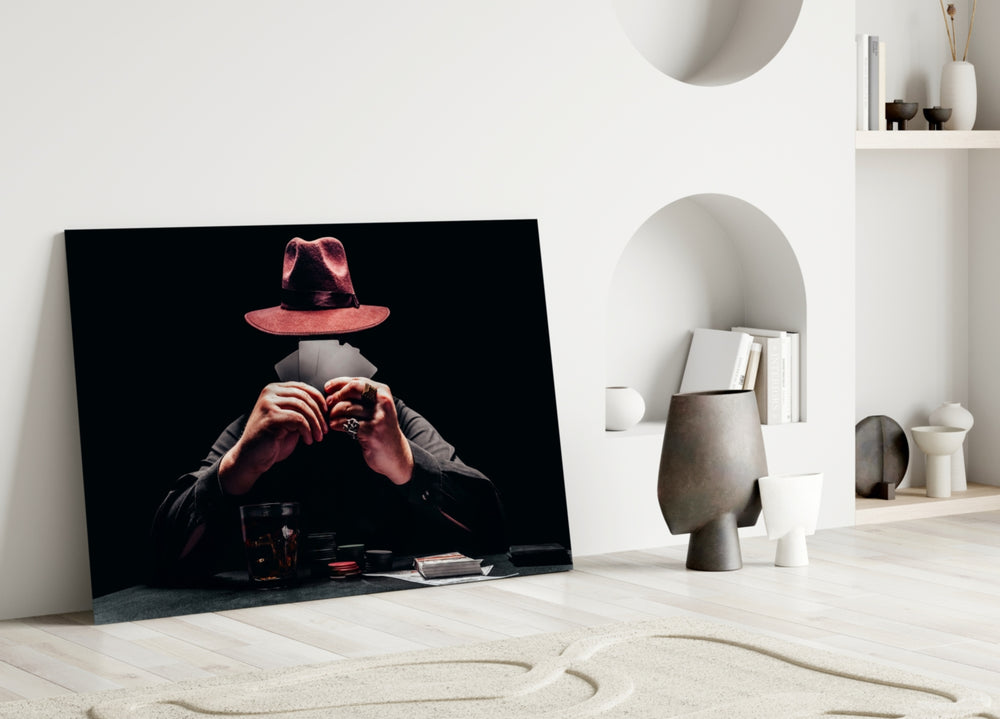 Close-up detail of burgundy fedora and fanned cards behind glass