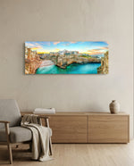 A cliffside Mediterranean town glowing at sunset above a turquoise cove. panoramic glass wall art A