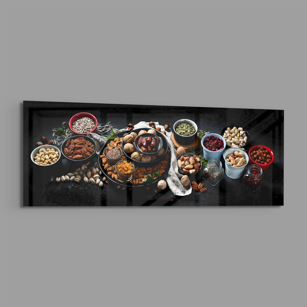 An overhead spread of mixed nuts, seeds, and dried fruit in bowls on a dark surface. panoramic glass wall art E