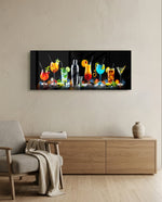 A row of vividly colored cocktails and a silver shaker glowing against a black bar backdrop. panoramic glass wall art A