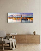 Panoramic Nordic old-town waterfront at dusk, warm street lights glowing along the quay beneath a soft pastel twilight sky. panoramic glass wall art A