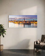 Panoramic Nordic old-town waterfront at dusk, warm street lights glowing along the quay beneath a soft pastel twilight sky. panoramic glass wall art C