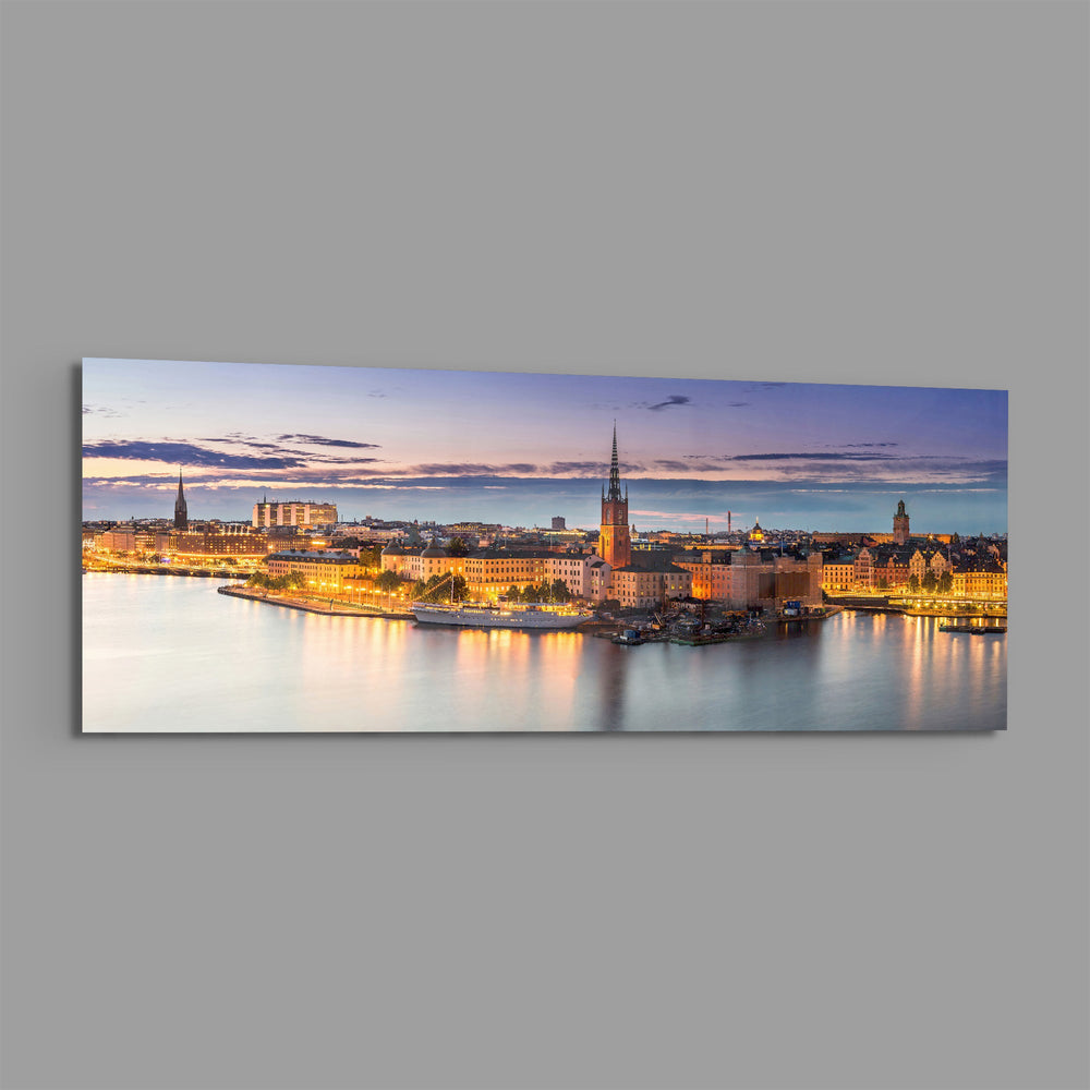 Panoramic Nordic old-town waterfront at dusk, warm street lights glowing along the quay beneath a soft pastel twilight sky. panoramic glass wall art E