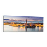 Panoramic Nordic old-town waterfront at dusk, warm street lights glowing along the quay beneath a soft pastel twilight sky. panoramic glass wall art F