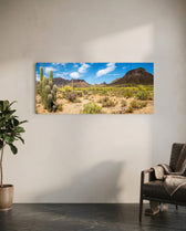Sun-drenched Sonoran desert panorama with towering saguaro cacti, scrub and rugged mountains under a bright blue sky dotted with puffy clouds. panoramic glass wall art C