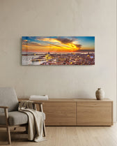 Aerial panoramic view of Venice at sunset, a great domed basilica and terracotta rooftops glowing beneath a fiery orange and blue sky over the lagoon. panoramic glass wall art A