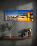 Panoramic harbor city at dusk, a great steel arch bridge lit gold beside a glittering downtown skyline mirrored in calm water. panoramic glass wall art D
