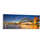 Panoramic harbor city at dusk, a great steel arch bridge lit gold beside a glittering downtown skyline mirrored in calm water. panoramic glass wall art F