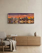 Panoramic metropolitan skyline at sunset, dense illuminated skyscrapers glowing beneath a fiery orange and violet sky, mirrored in the river below. panoramic glass wall art A