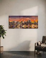 Panoramic metropolitan skyline at sunset, dense illuminated skyscrapers glowing beneath a fiery orange and violet sky, mirrored in the river below. panoramic glass wall art C
