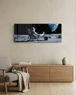 A spacesuited astronaut lounging in a deck chair on the lunar surface while planet Earth hangs in the black sky. panoramic glass wall art A