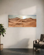 Rolling golden sand dunes rippling toward the horizon under a soft, hazy sun low in a pale sky. panoramic glass wall art C