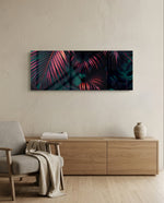 A moody close-up of tropical palm fronds glowing neon pink against deep, dark green jungle foliage. panoramic glass wall art A