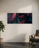A moody close-up of tropical palm fronds glowing neon pink against deep, dark green jungle foliage. panoramic glass wall art C