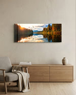 A mirror-calm lake at sunrise reflecting autumn forest, distant mountains, and a glowing cloudy sky. panoramic glass wall art A