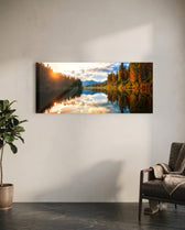 A mirror-calm lake at sunrise reflecting autumn forest, distant mountains, and a glowing cloudy sky. panoramic glass wall art C