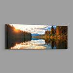 A mirror-calm lake at sunrise reflecting autumn forest, distant mountains, and a glowing cloudy sky. panoramic glass wall art E