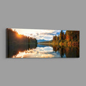 A mirror-calm lake at sunrise reflecting autumn forest, distant mountains, and a glowing cloudy sky. panoramic glass wall art E