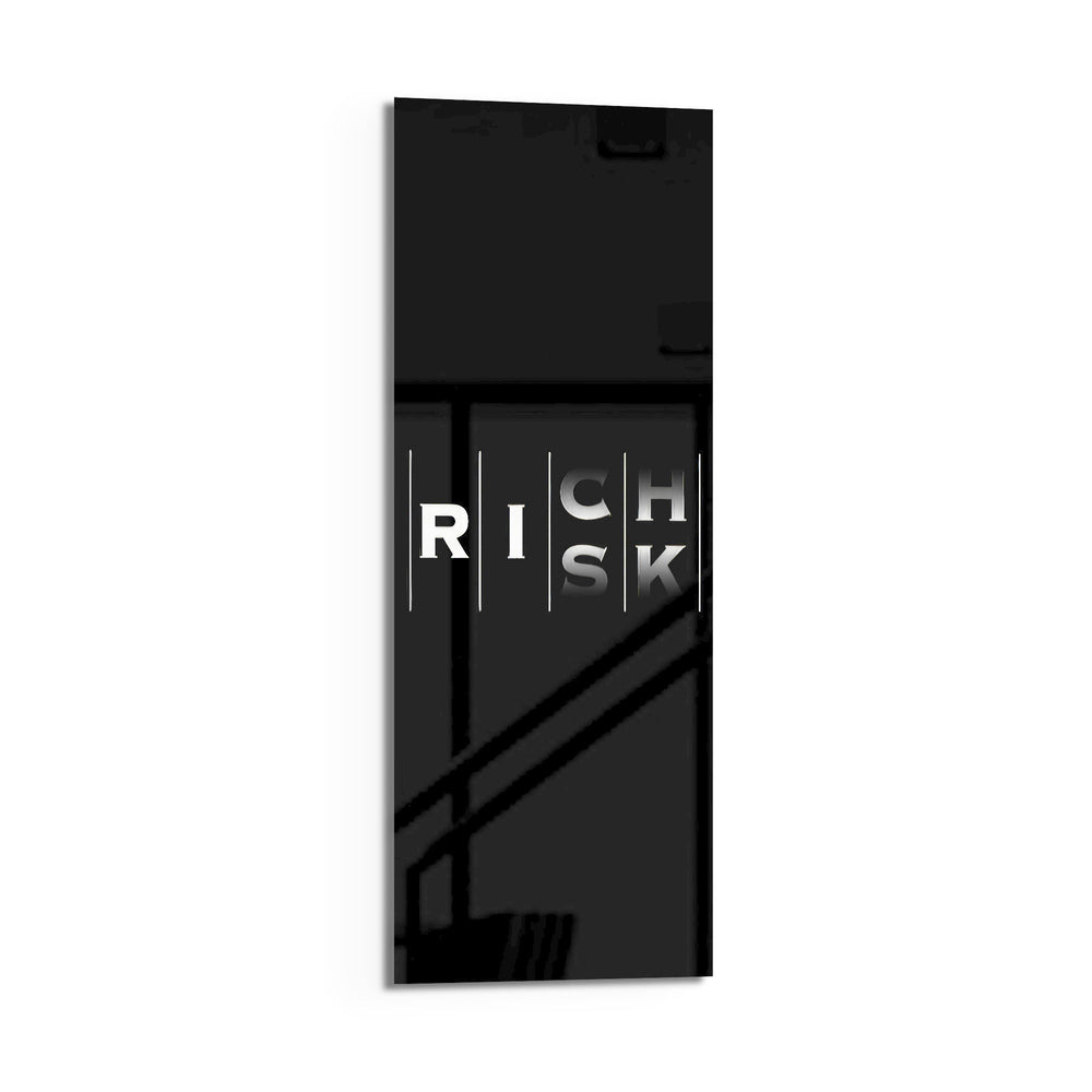 Minimalist black typography panel where the words "RISK" and "RICH" interlock in a single vertical column of white letters. panoramic glass wall art D